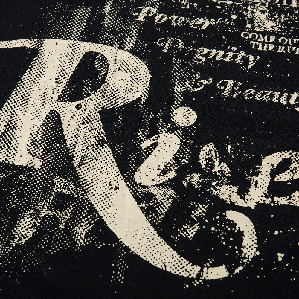Male model wearing black ink splatter graffiti letter streetwear tee in urban lifestyle setting | TeenStylo