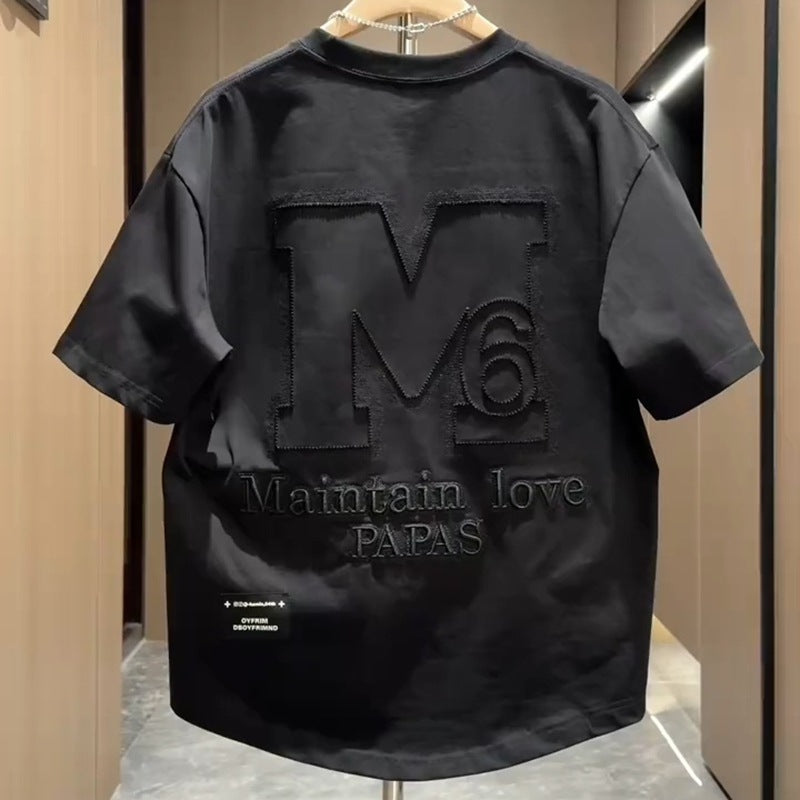 Man wearing orange designer letter M embroidered half sleeve top, streetwear lifestyle look | TeenStylo