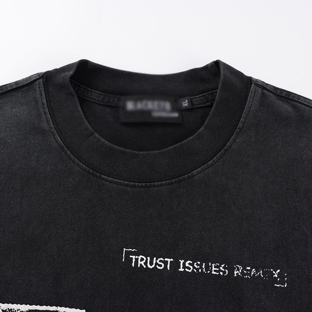 Aged black washed t-shirt fabric detail showing faded pattern print texture streetwear style TeenStylo