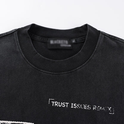 Aged black washed t-shirt fabric detail showing faded pattern print texture streetwear style TeenStylo