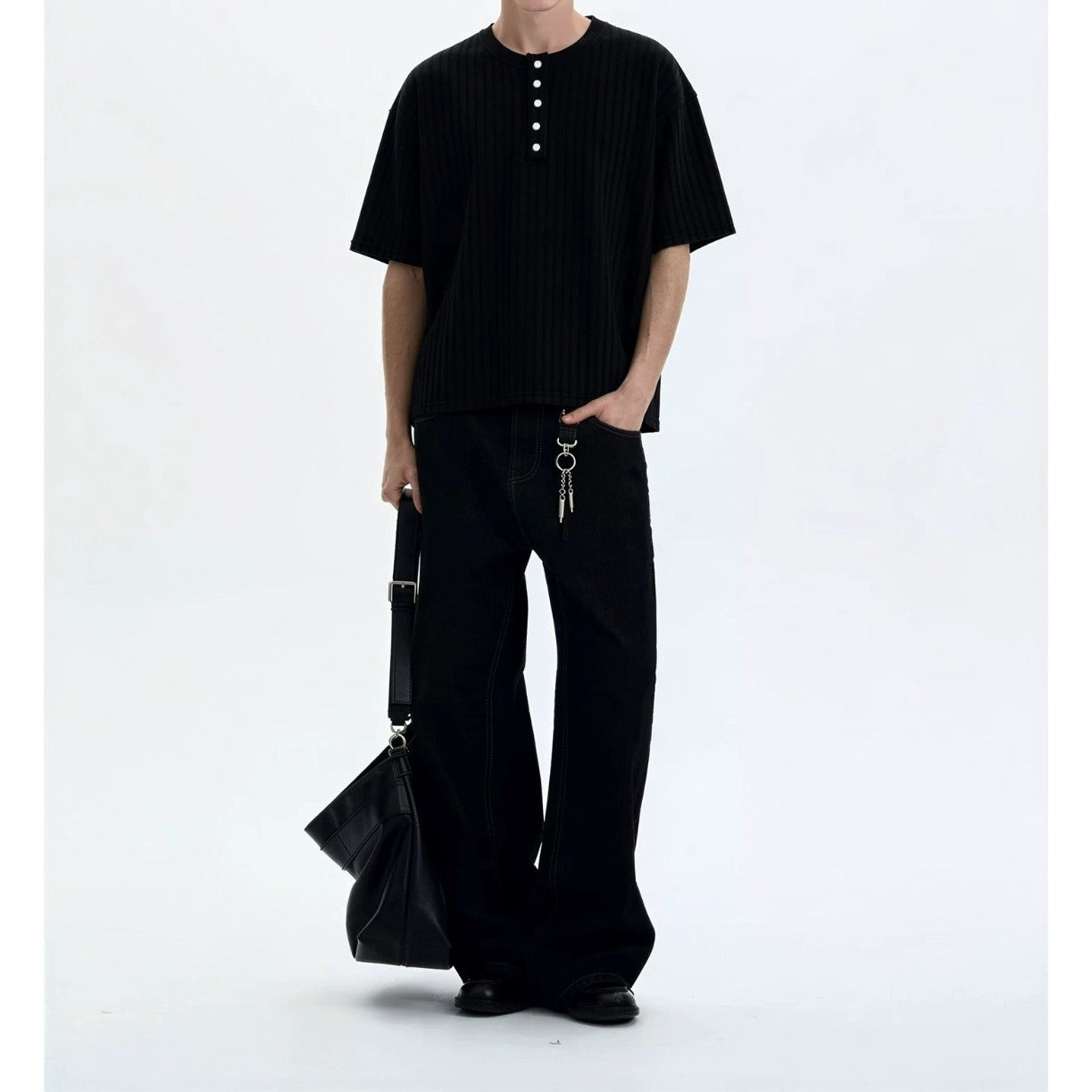 Man wearing black retro knitted henley collar short sleeve t-shirt in casual streetwear lifestyle setting | TeenStylo
